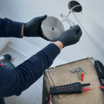 Installer luminaire plafond : fixations adaptées sur plafond percé, installateur en gants